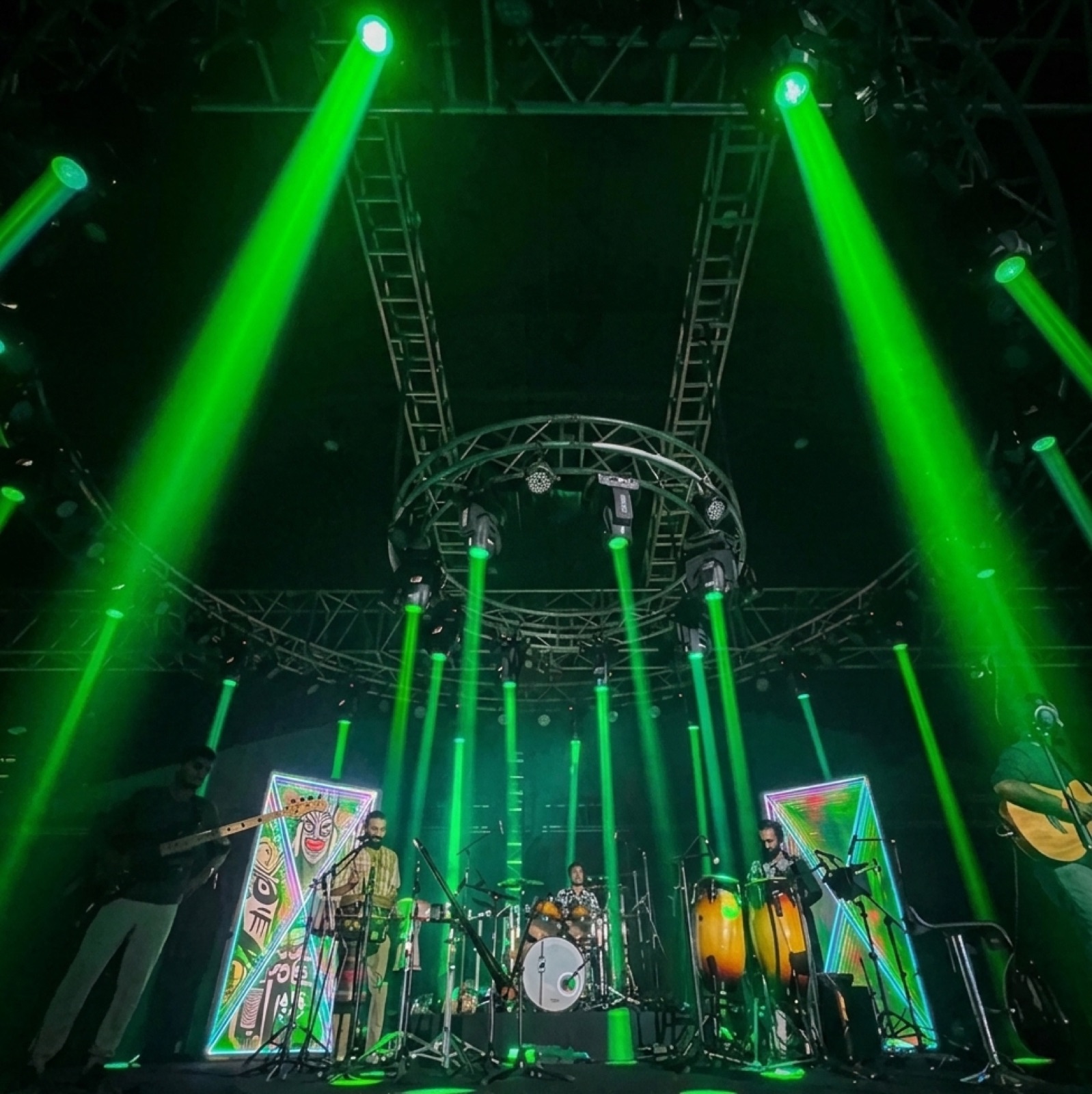 A band performing in green beam light at Namaste NFT
